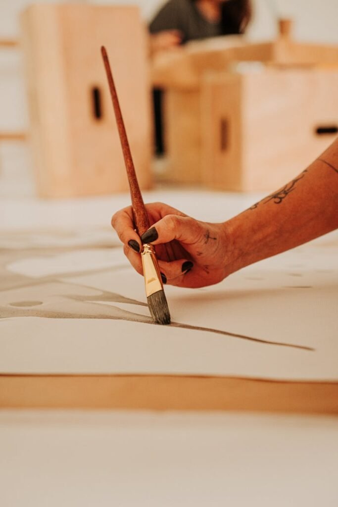 Close-up of a hand painting abstract art on canvas with a brush in an artistic studio.